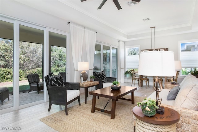 sunroom featuring a tray ceiling, a wealth of natural light, and ceiling fan