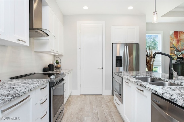 kitchen featuring white cabinetry, sink, wall chimney exhaust hood, stainless steel appliances, and light wood-type flooring