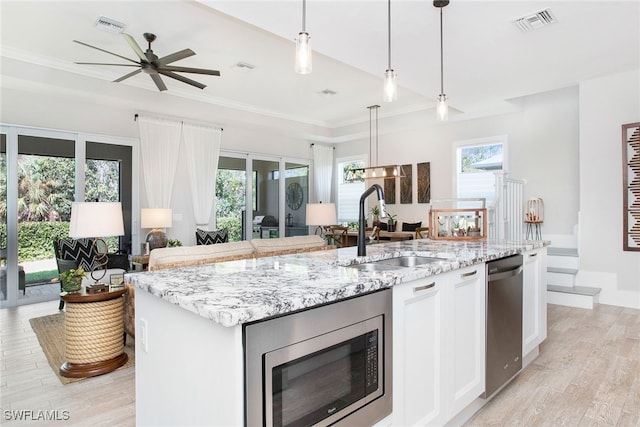 kitchen featuring a wealth of natural light, white cabinetry, sink, a kitchen island with sink, and appliances with stainless steel finishes