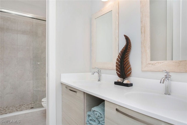 bathroom with a tile shower, tile patterned flooring, vanity, and toilet