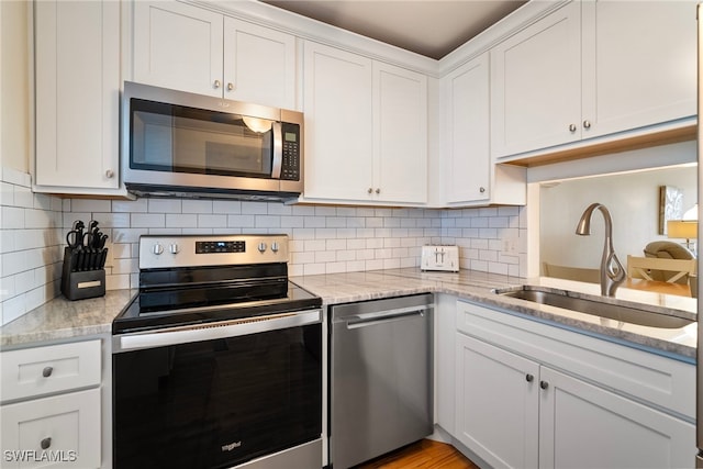 kitchen featuring light stone counters, sink, white cabinets, and appliances with stainless steel finishes