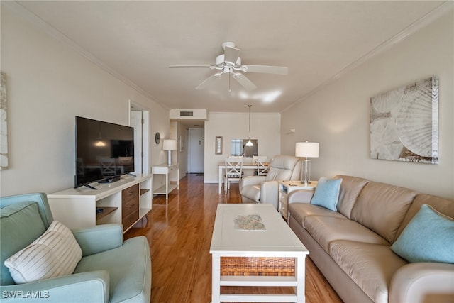 living room with wood-type flooring, ceiling fan, and ornamental molding