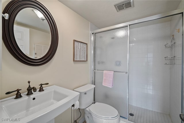 bathroom featuring toilet, an enclosed shower, and sink