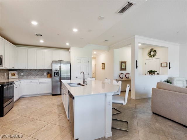 kitchen featuring white cabinets, appliances with stainless steel finishes, an island with sink, and sink