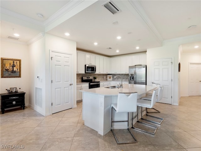 kitchen with a kitchen island with sink, white cabinetry, sink, and stainless steel appliances