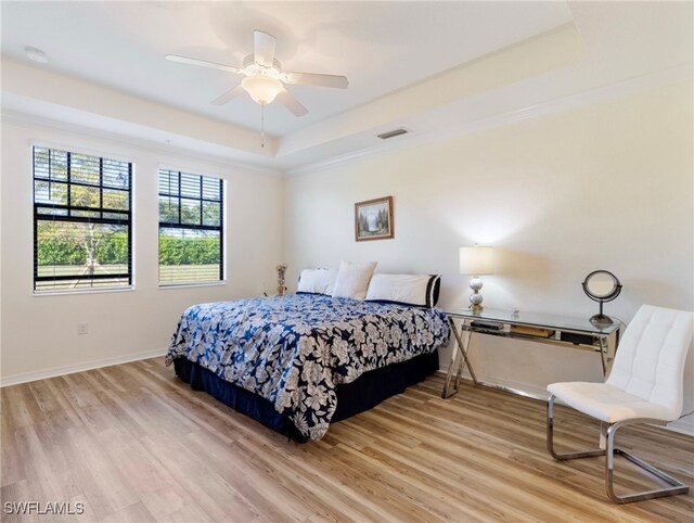 bedroom featuring a raised ceiling, light hardwood / wood-style flooring, and ceiling fan