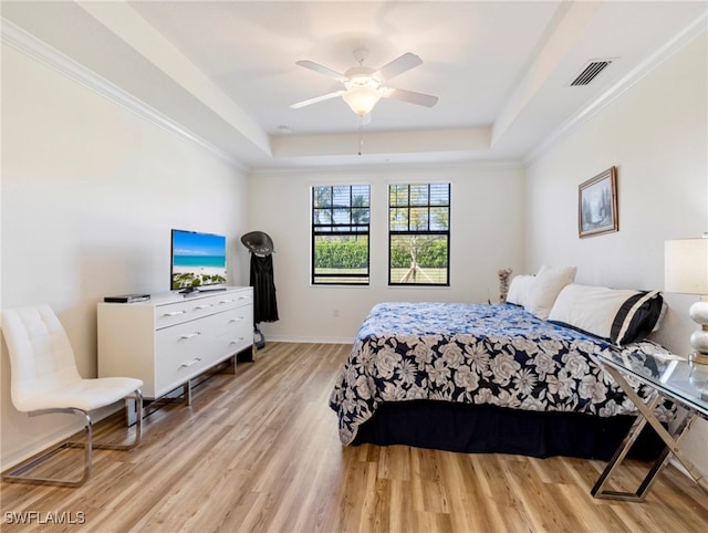 bedroom featuring ceiling fan, light wood-type flooring, crown molding, and a tray ceiling