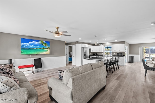 living room featuring ceiling fan and light hardwood / wood-style flooring