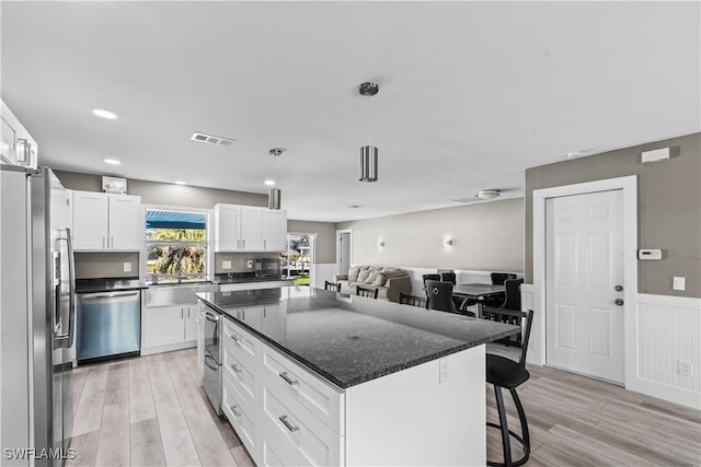 kitchen featuring white cabinetry, a center island, stainless steel appliances, and light wood-type flooring