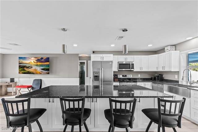 kitchen with stainless steel appliances, white cabinetry, hanging light fixtures, and sink