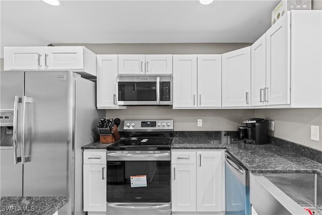 kitchen with dark stone countertops, white cabinets, and appliances with stainless steel finishes