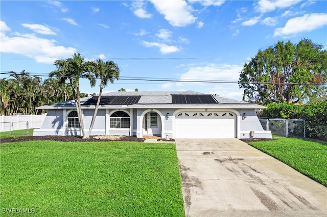 ranch-style home with solar panels, a garage, and a front lawn