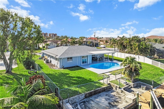 rear view of property with a patio area, a fenced in pool, and a yard