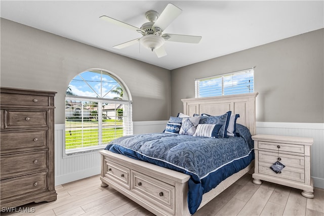 bedroom featuring ceiling fan, light wood-type flooring, and multiple windows