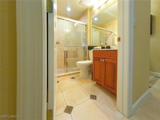 bathroom featuring tile patterned floors, vanity, a shower with shower door, and toilet