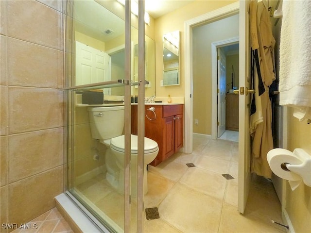 bathroom with tile patterned flooring, vanity, toilet, and a shower with shower door