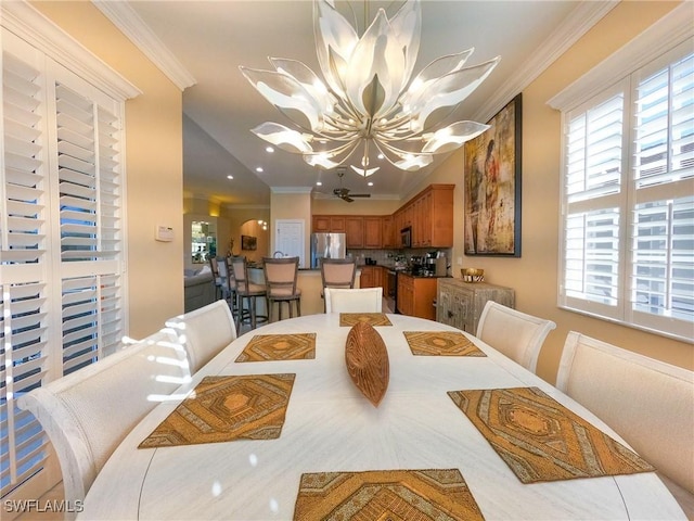 dining area with crown molding and ceiling fan with notable chandelier