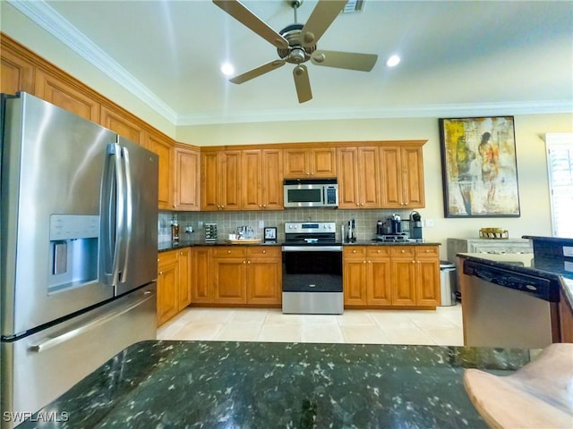 kitchen with ceiling fan, appliances with stainless steel finishes, dark stone counters, light tile patterned floors, and ornamental molding