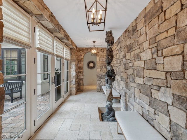 hallway with french doors and a chandelier