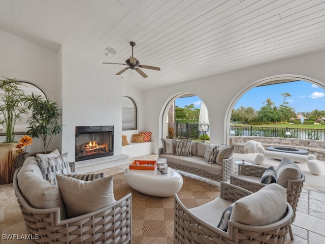 living room featuring ceiling fan, a fireplace, and a water view