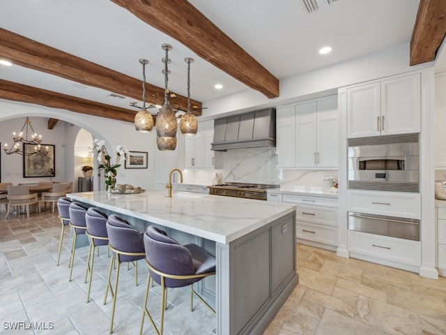 kitchen with stainless steel appliances, beamed ceiling, pendant lighting, a spacious island, and custom range hood