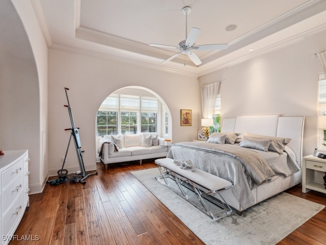 bedroom featuring a raised ceiling, ceiling fan, dark hardwood / wood-style flooring, and crown molding