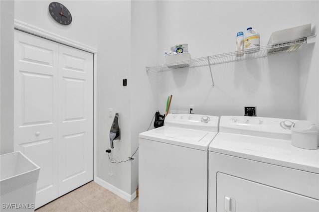 clothes washing area featuring washing machine and dryer and light tile patterned floors