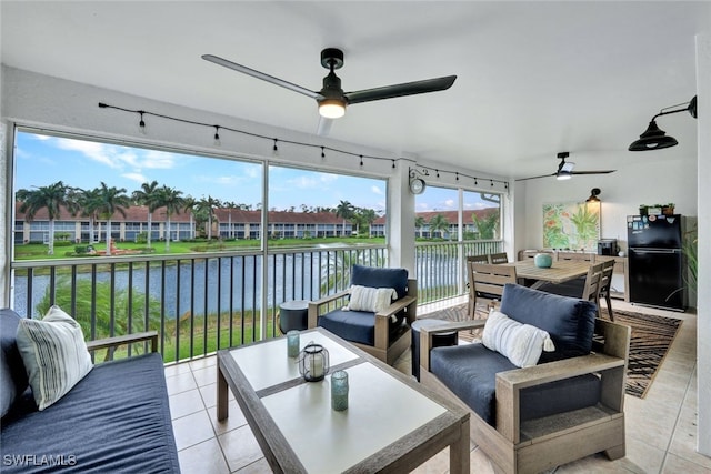 sunroom with ceiling fan and a water view