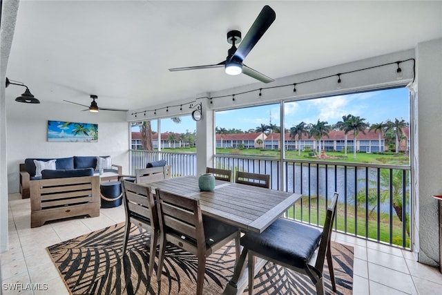 sunroom / solarium with ceiling fan and a water view