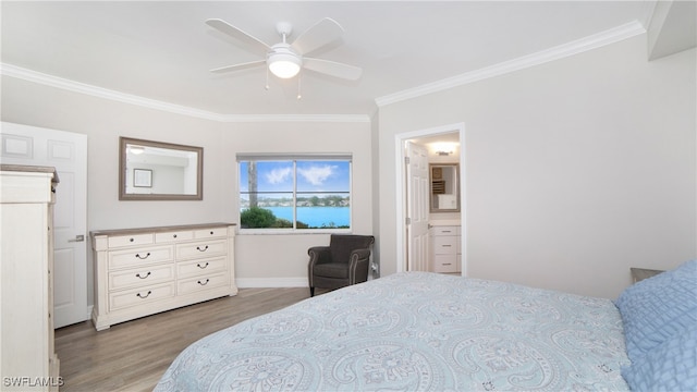 bedroom featuring ceiling fan, ensuite bath, wood-type flooring, and crown molding