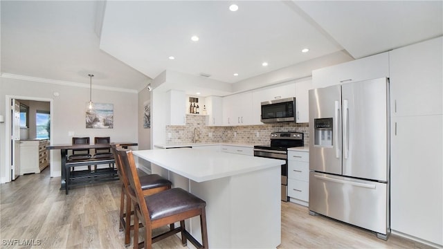 kitchen with appliances with stainless steel finishes, decorative light fixtures, tasteful backsplash, white cabinets, and light wood-type flooring