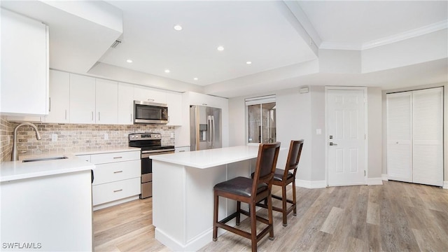 kitchen with sink, tasteful backsplash, light wood-type flooring, stainless steel appliances, and white cabinets