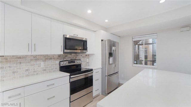 kitchen featuring backsplash, light hardwood / wood-style flooring, white cabinets, and appliances with stainless steel finishes