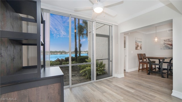 dining space with a water view, a healthy amount of sunlight, ornamental molding, and light hardwood / wood-style flooring