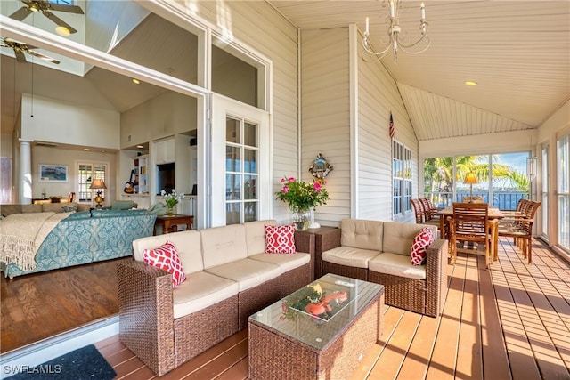 sunroom with plenty of natural light, lofted ceiling, and ceiling fan with notable chandelier