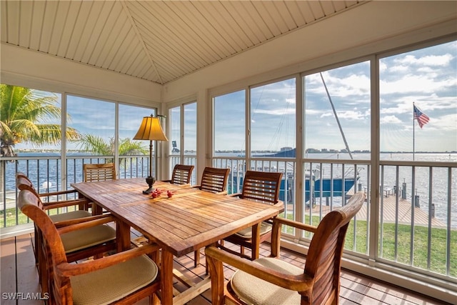 sunroom featuring a water view, vaulted ceiling, and a healthy amount of sunlight