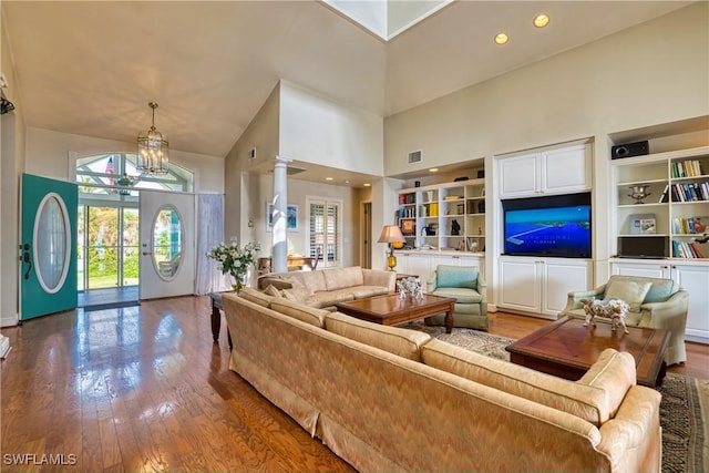 living room featuring plenty of natural light, high vaulted ceiling, wood-type flooring, and an inviting chandelier