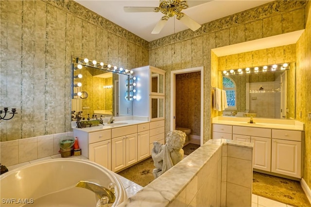 bathroom with ceiling fan, vanity, and tiled bath