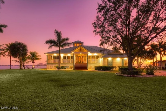 view of front of house featuring a sunroom and a yard