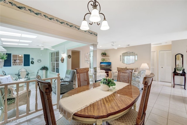 dining room featuring ceiling fan with notable chandelier, light tile patterned floors, and a skylight