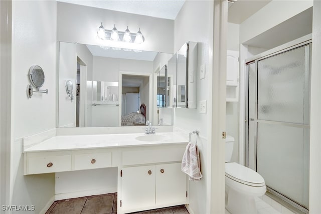 bathroom featuring tile patterned flooring, a shower with door, vanity, and toilet