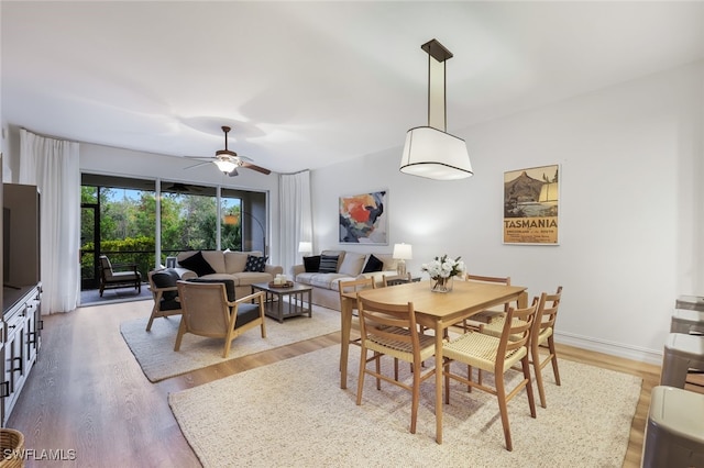 dining space with baseboards, a ceiling fan, and wood finished floors