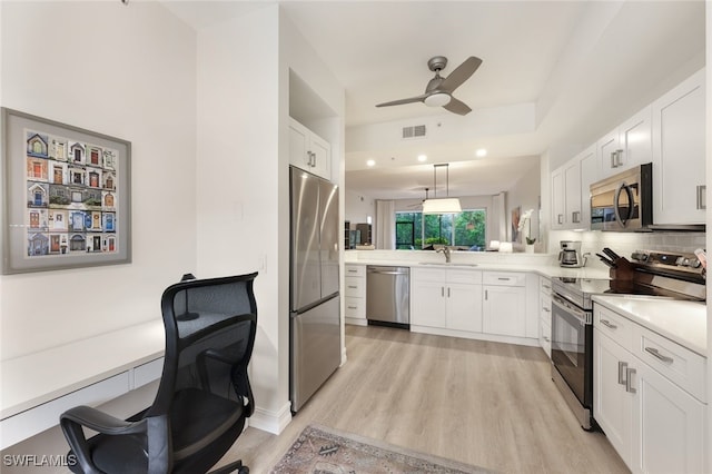 kitchen featuring a peninsula, visible vents, light wood-style floors, light countertops, and appliances with stainless steel finishes