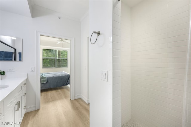 ensuite bathroom featuring ornamental molding, connected bathroom, vanity, wood finished floors, and tiled shower