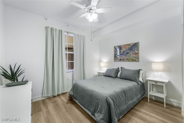 bedroom featuring ceiling fan, light wood-style flooring, and baseboards