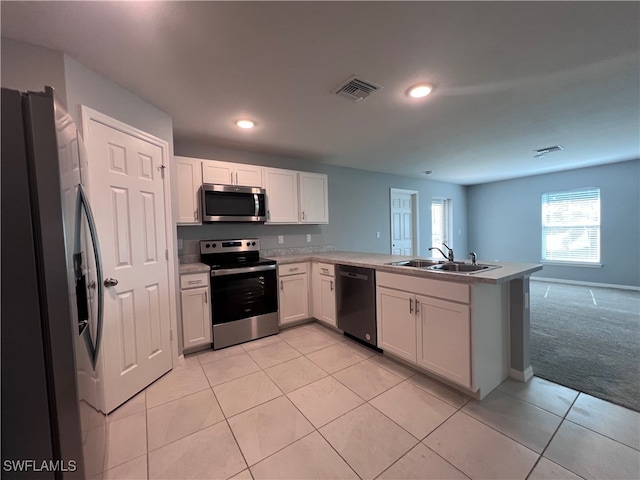 kitchen featuring sink, kitchen peninsula, light colored carpet, white cabinetry, and stainless steel appliances