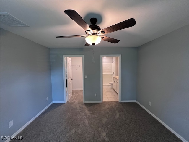 unfurnished bedroom with ensuite bath, light colored carpet, ceiling fan, a spacious closet, and a closet