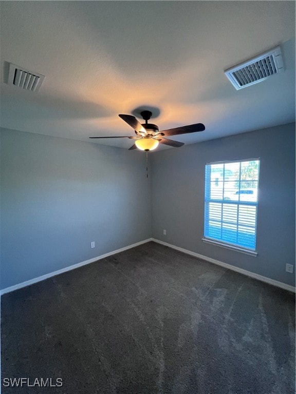 spare room featuring dark carpet and ceiling fan