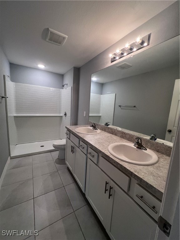 bathroom with a shower, tile patterned flooring, vanity, and toilet