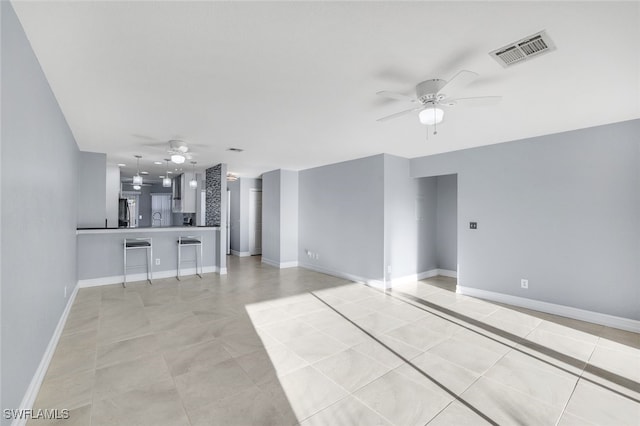 unfurnished living room featuring ceiling fan, sink, and light tile patterned flooring